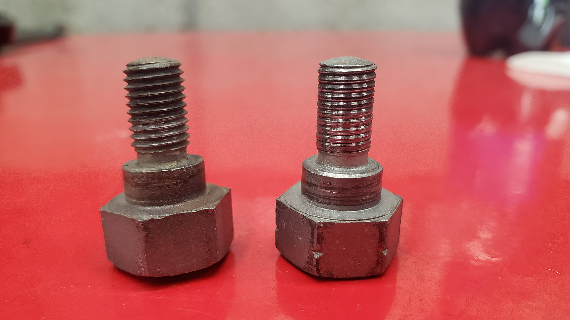 Unique hinge pivot bolts have a shoulder. Normal (left) and damaged threads (right). 